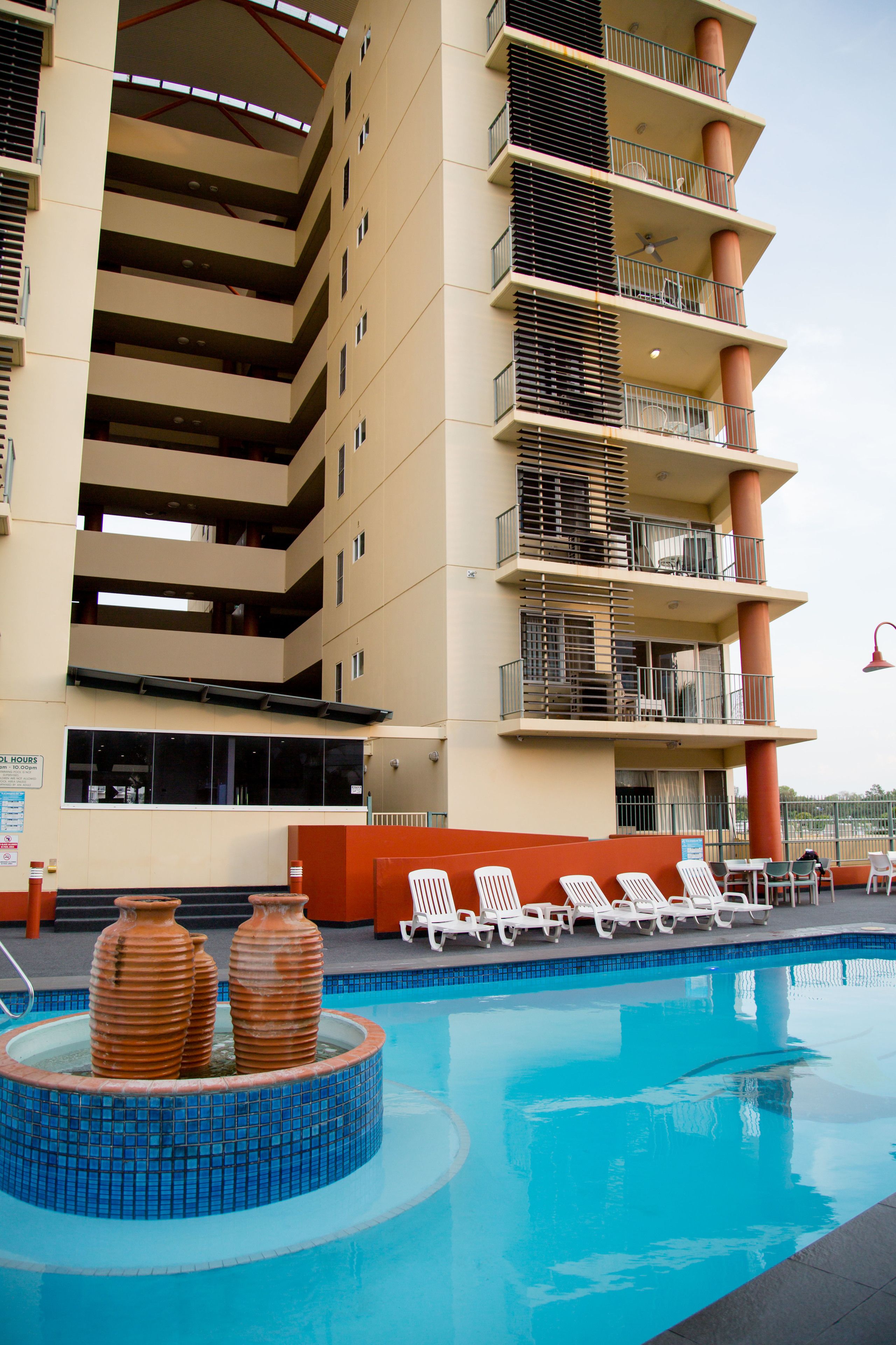 A hotel with a swimming pool, multiple balconies, and outdoor seating.