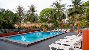 Une piscine avec des chaises longues et des palmiers.