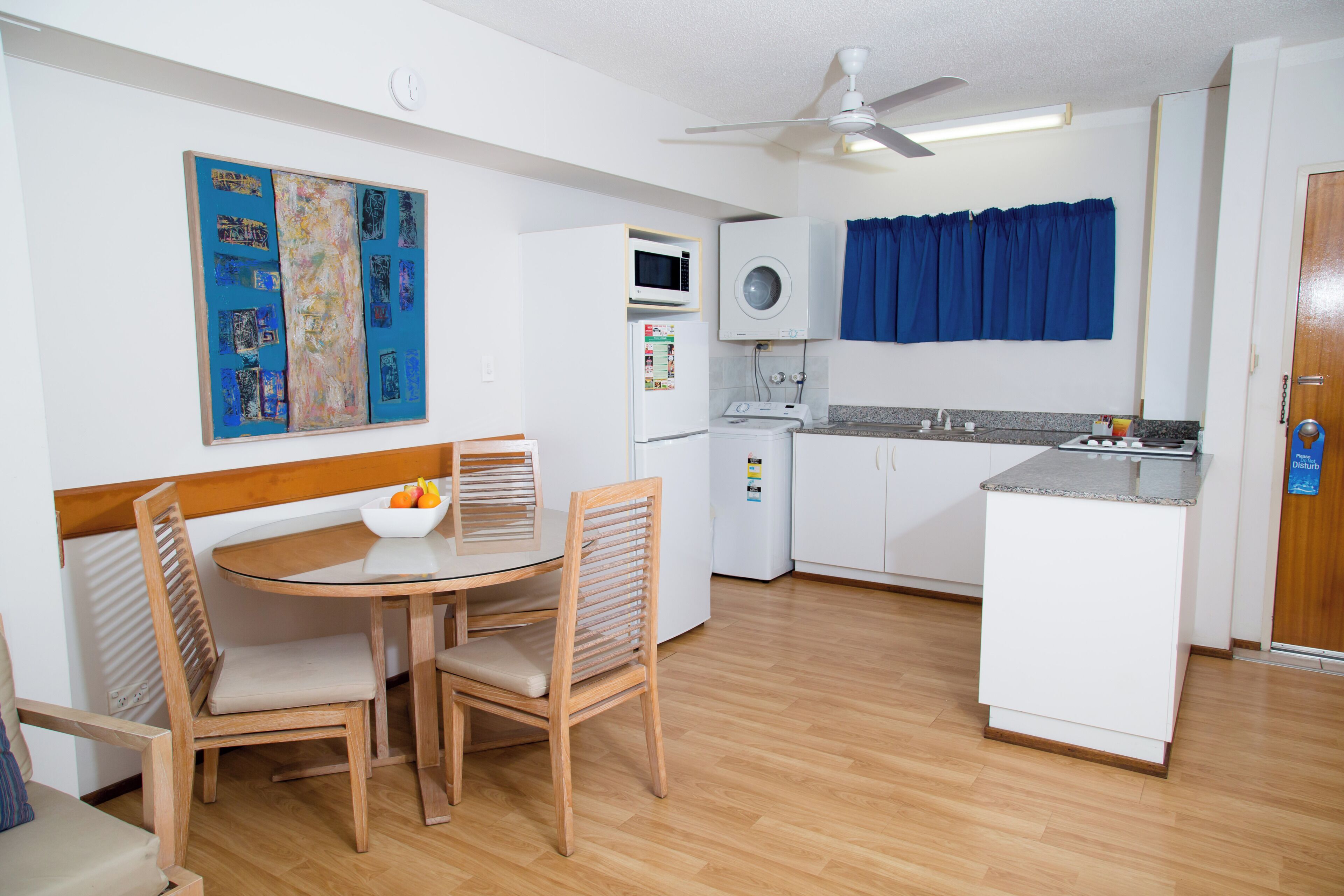 Cocina compacta con comedor, que incluye microondas, refrigerador pequeño y ventilador de techo.