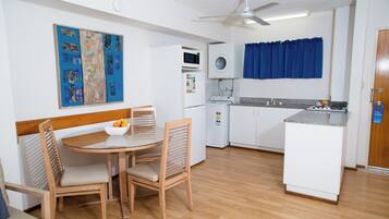 Cocina compacta con comedor, que incluye microondas, refrigerador pequeño y ventilador de techo.