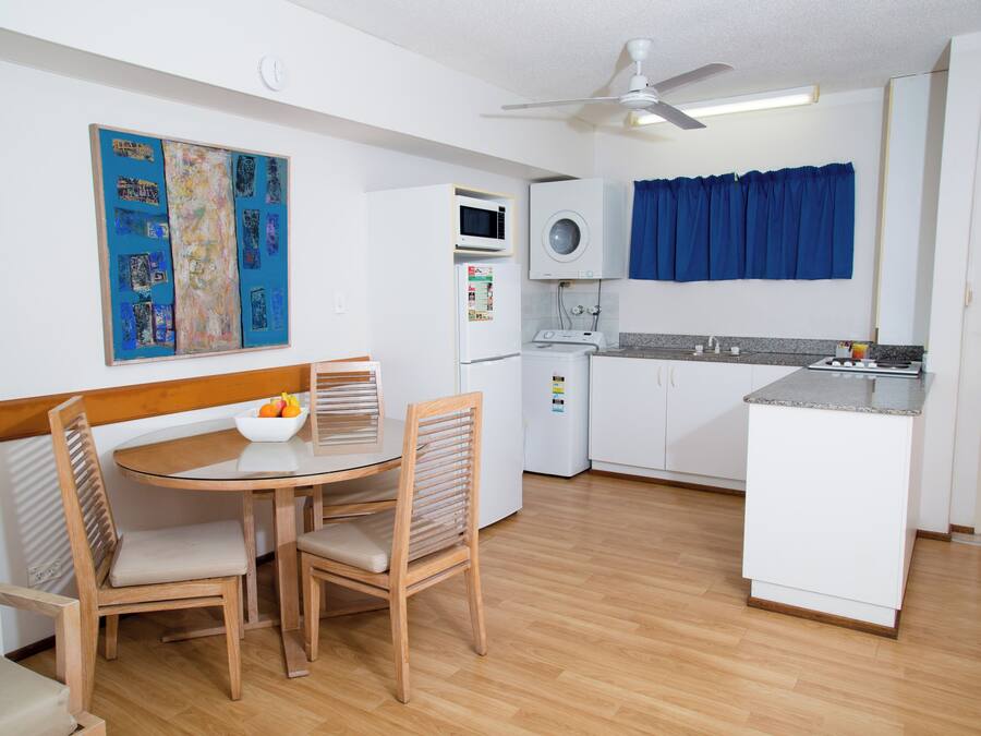 Cocina compacta con comedor, que incluye microondas, refrigerador pequeño y ventilador de techo.