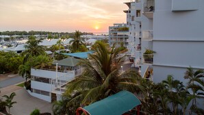 Un hôtel de grande hauteur doté de nombreux balcons, de palmiers et offrant une vue imprenable sur le coucher de soleil.