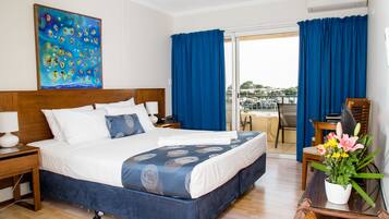 Habitación de hotel con una cama grande, un escritorio, una silla, una ventana con cortinas y vistas al exterior.