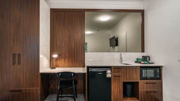 Una kitchenette compacta con refrigerador, microondas y lavamanos.