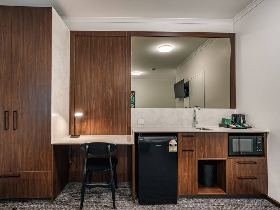 Una kitchenette compacta con refrigerador, microondas y lavamanos.