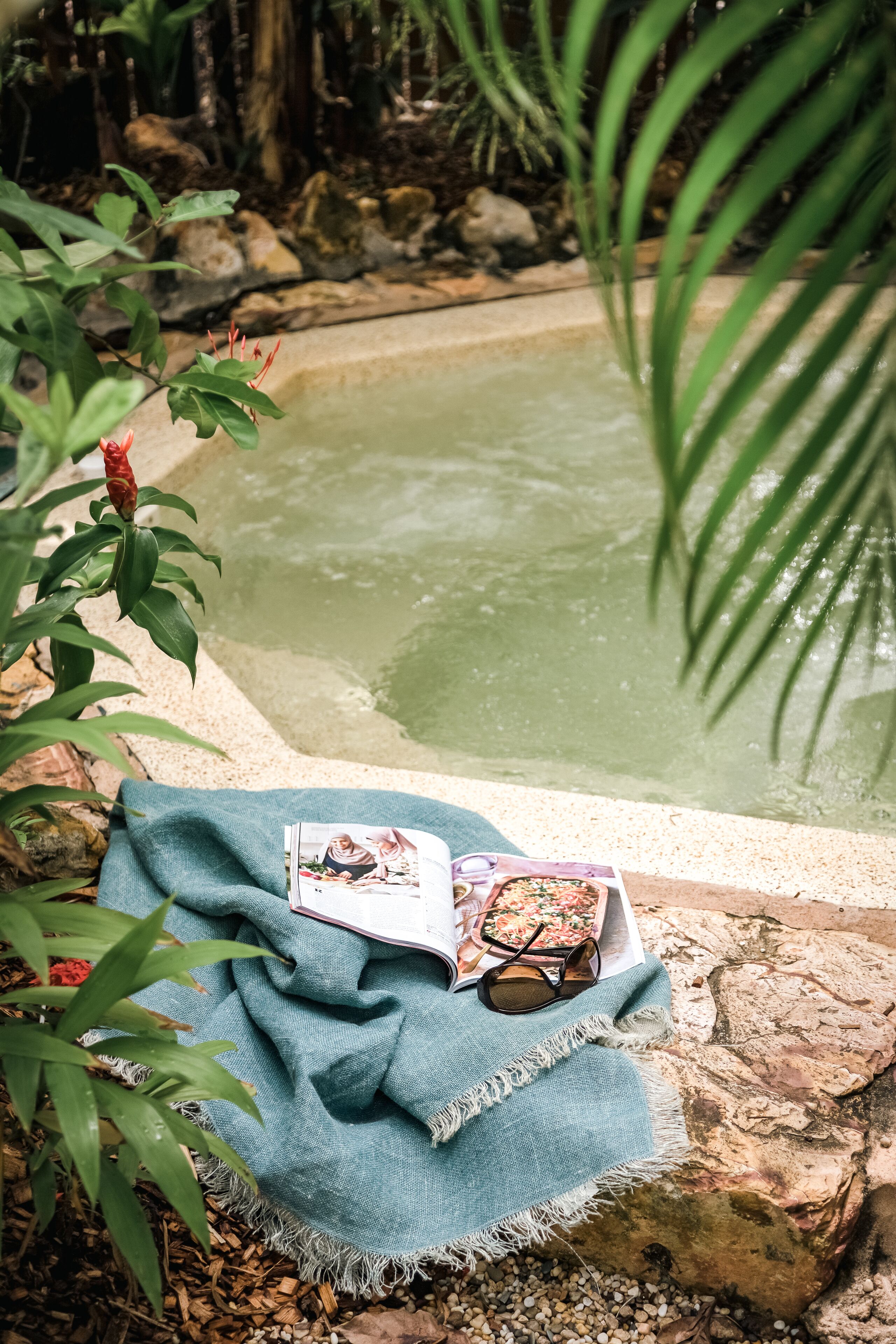 A small pond with a blue cloth and a book on a rock.