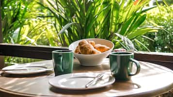 Una mesa de desayuno con cruasanes, un bol y dos tazas verdes.