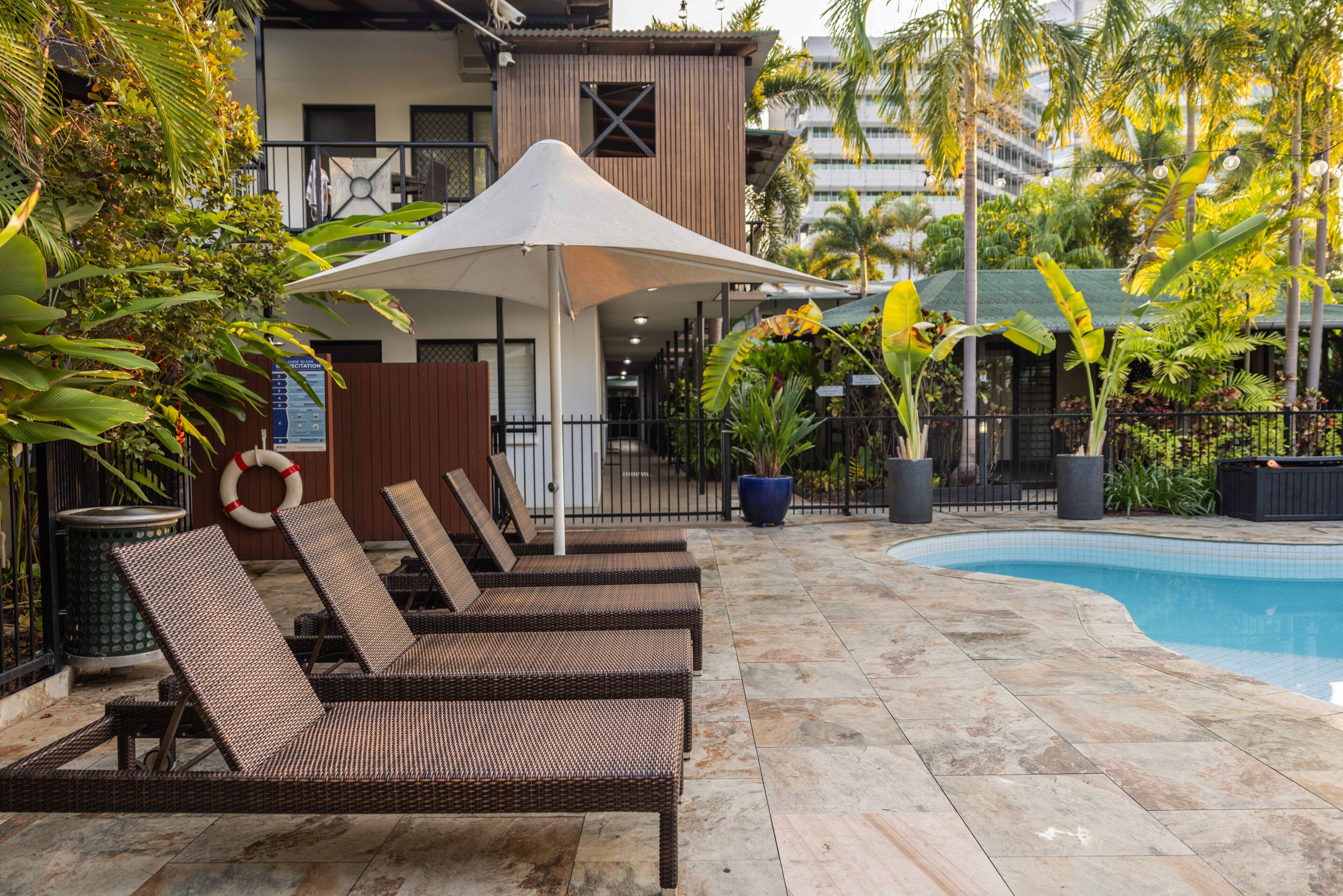 A poolside area with lounge chairs, a covered seating area, and a swimming pool.