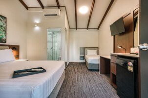 Una habitación de hotel con una cama, un escritorio, un refrigerador y un televisor.