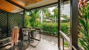 Un espacio al aire libre cubierto con una mesa y sillas, rodeado de vegetación y vistas a una zona residencial.