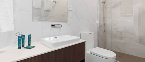 Une salle de bain moderne avec un lavabo blanc, un miroir et des toilettes.
