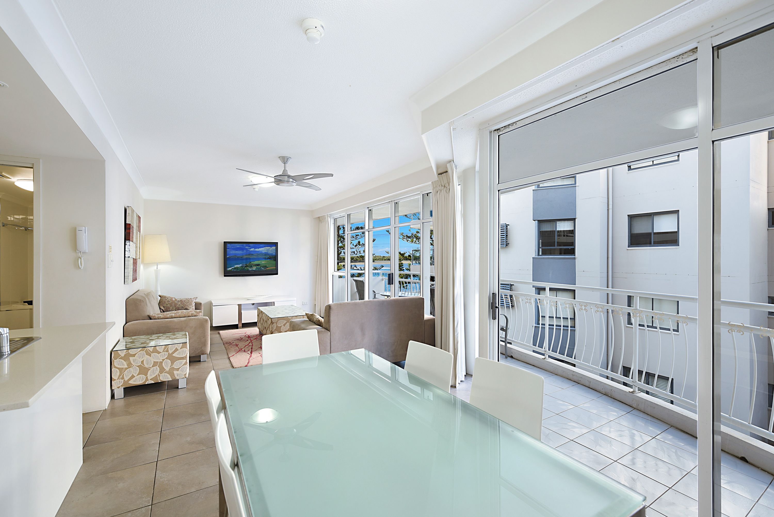 A modern hotel room with a balcony, a dining area, and a living space.