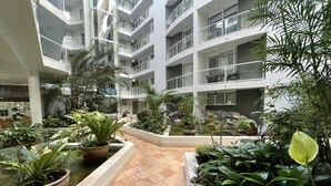 A multi-level atrium with a central water feature surrounded by potted plants and a tiled floor. - Atrium Resort (Biggera Waters)