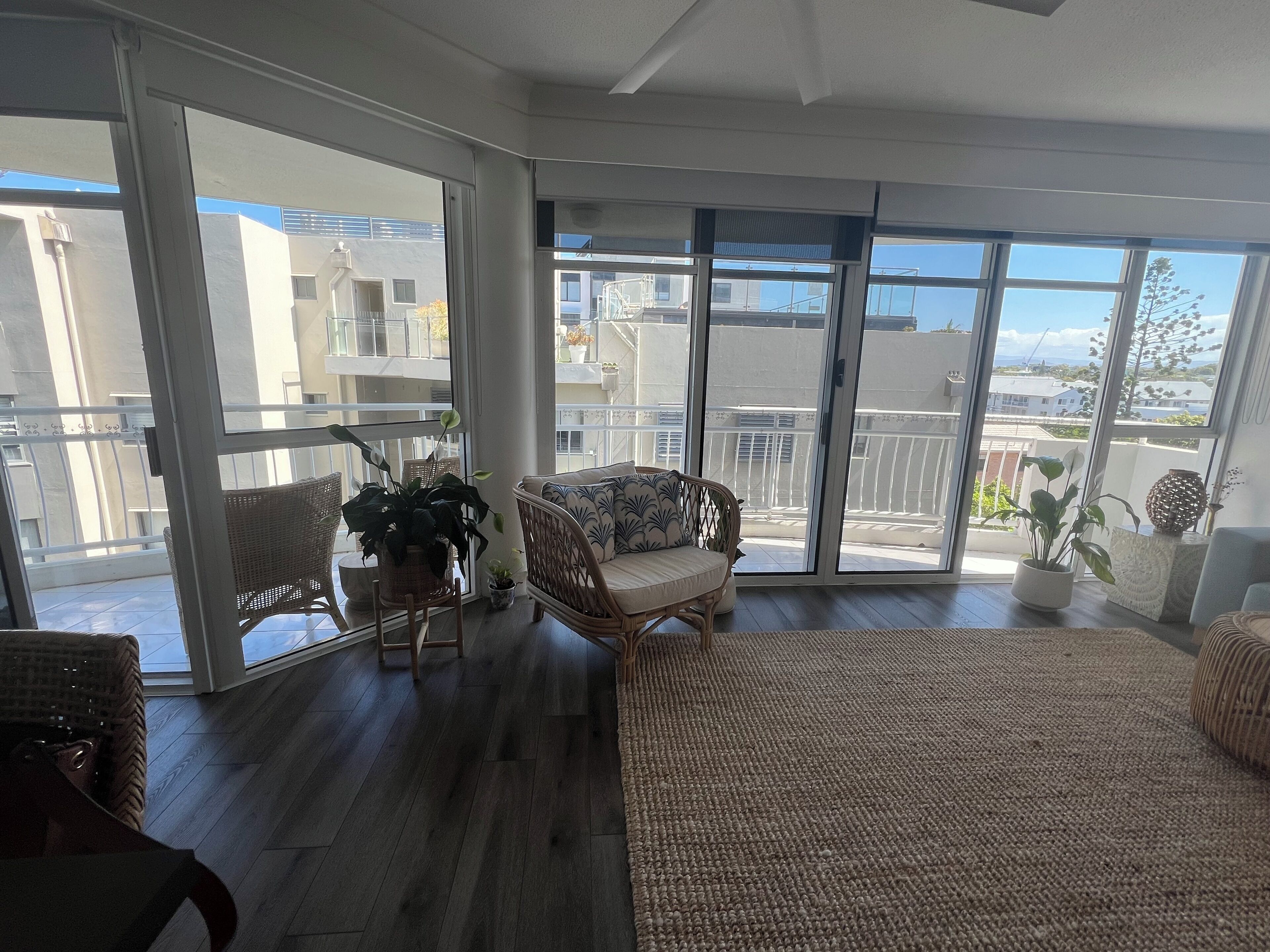 Ein geräumiger Balkon mit Rattanmöbeln, einem kleinen Tisch und Blumentöpfen.