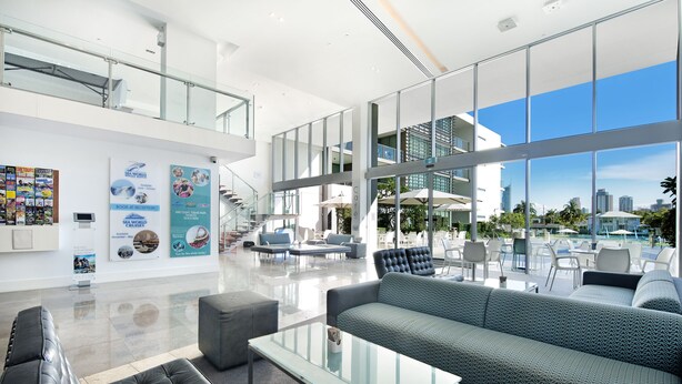 A spacious lobby with a high ceiling, a staircase, and a seating area with a sofa and armchairs.