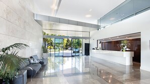 A modern lobby with a reception desk, seating area, and glass doors leading outside.