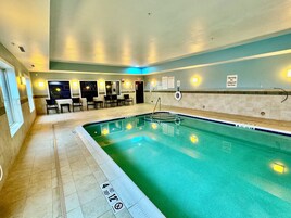 Una piscina con indicador de profundidad, un área de descanso con sillas y un cartel que indica que no hay salvavidas de servicio.