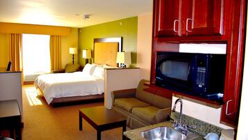 A hotel room with a bed, a sofa, a desk, a microwave, and a sink.
