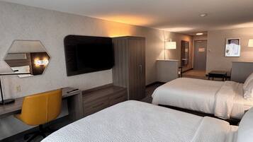 A hotel room with two beds, a desk, a chair, a TV, and a mirror.