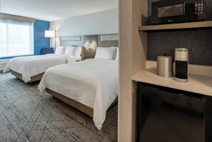 Een hotelkamer met twee bedden, een magnetron, een Keurig koffiezetapparaat en een koelkast.