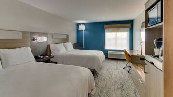 A hotel room with two beds, a desk, a chair, a microwave, and a coffee maker.