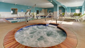 A hot tub area with a pool, seating, and a blue-tiled wall.