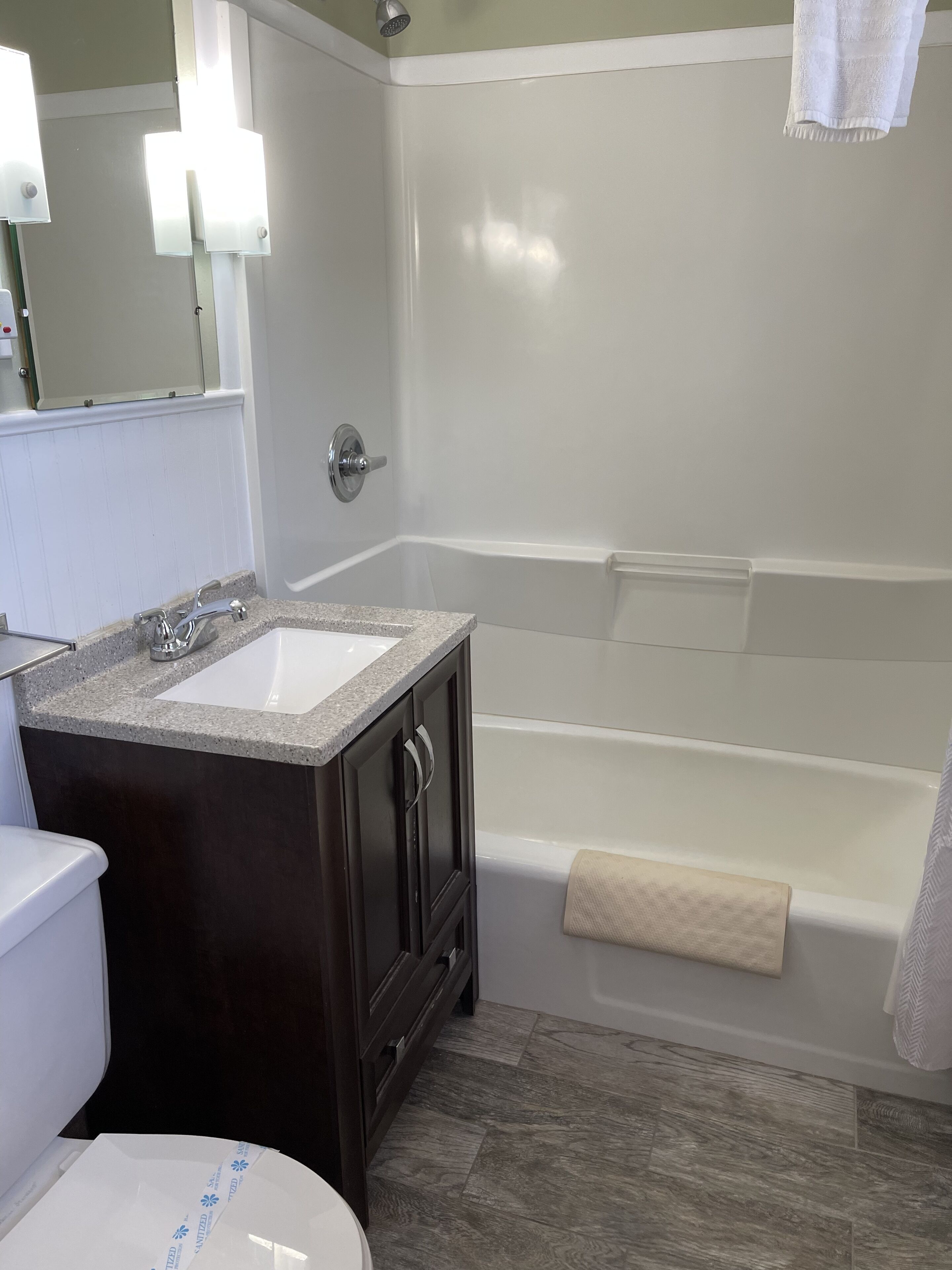 A bathroom with a white sink, dark wooden vanity, and a white bathtub.