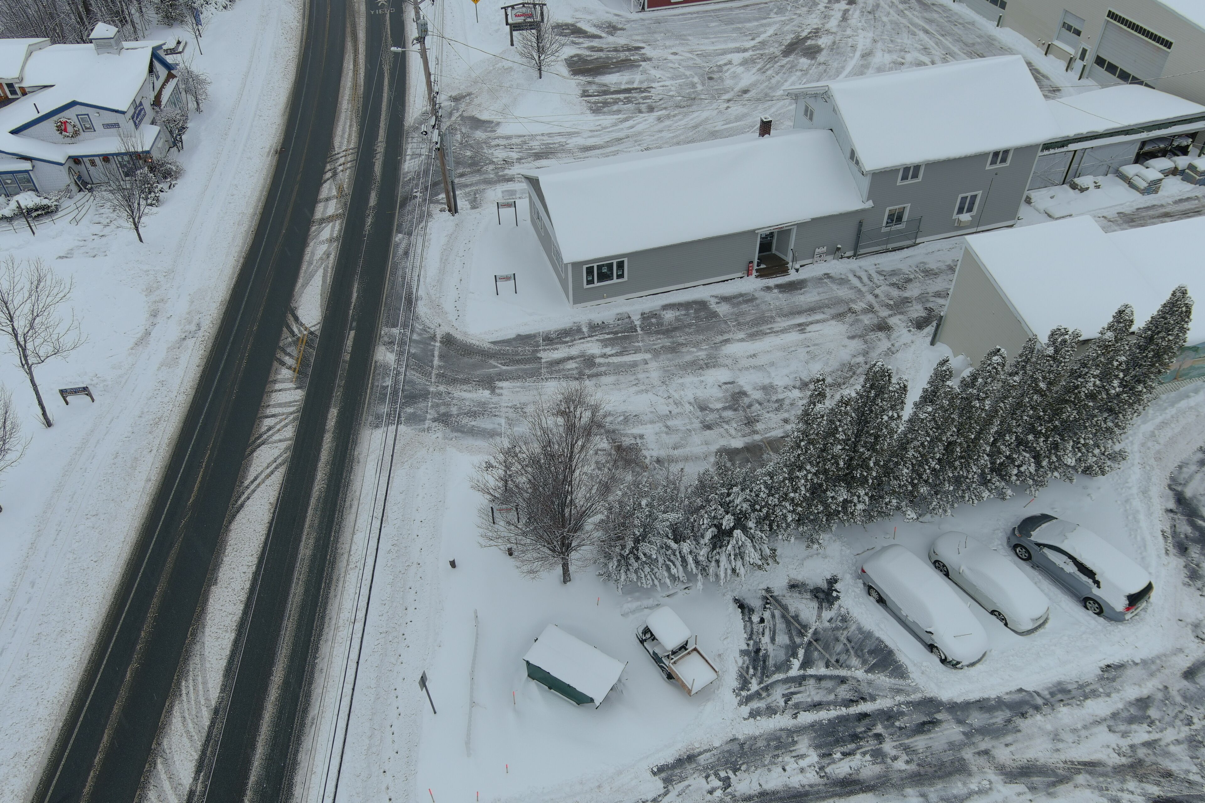 Un estacionamiento cubierto de nieve con varios coches y un edificio de techo plano.
