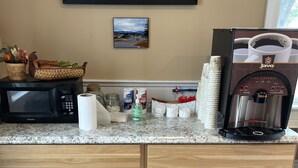 Una cocina equipada con microondas, cafetera y armarios.