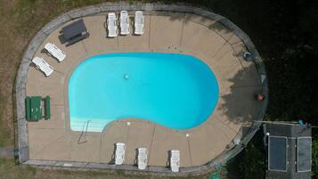 Relax by the pool surrounded by lounge chairs and benches, with a safety fence for a secure environment.