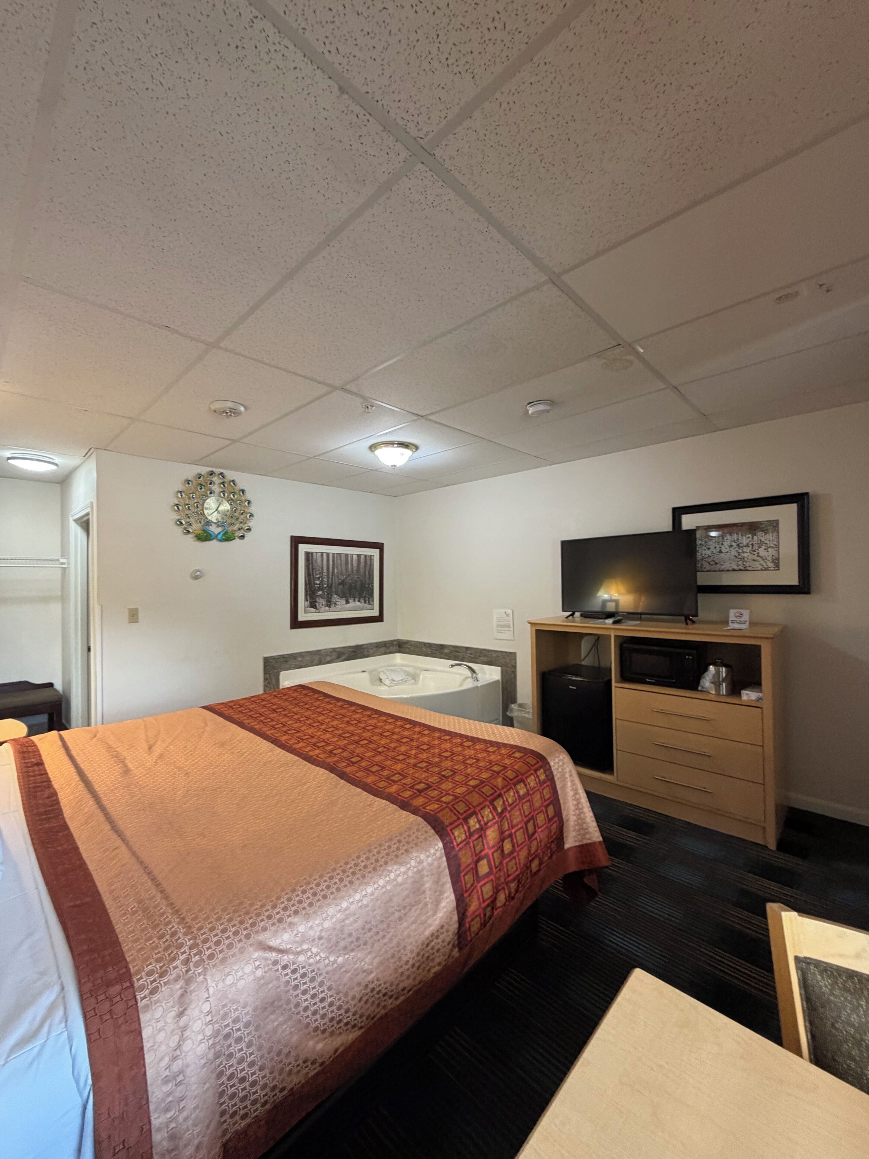 A hotel room with a bed, a desk, a television, a microwave, and a small cabinet.