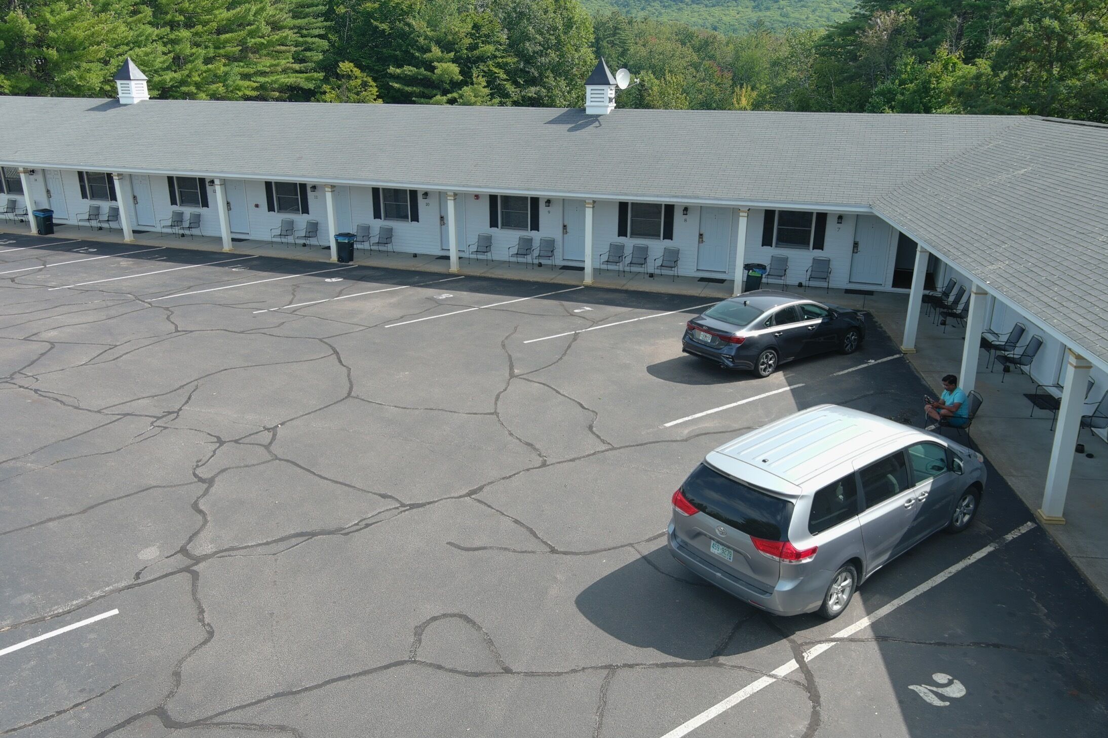 Un motel doté d’un parking, d’une zone d’attente abritée et d’un bâtiment à la façade blanche.