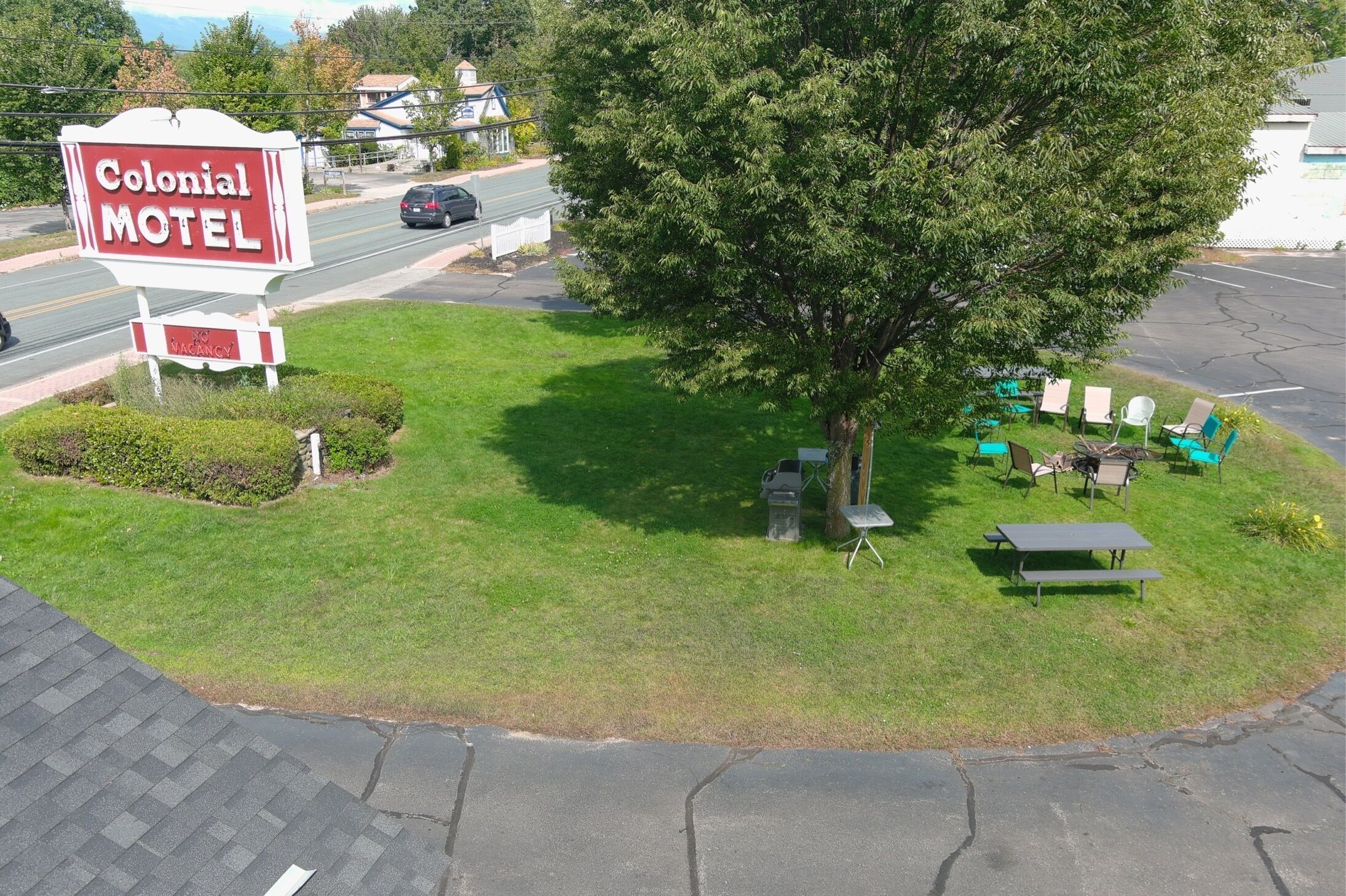 A motel sign, a parking lot, and outdoor seating with tables and chairs.