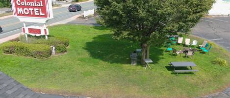 A motel sign, a parking lot, and outdoor seating with tables and chairs.