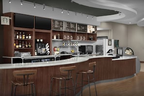 A modern bar area with a curved counter, bar stools, and a variety of beverages and glassware.