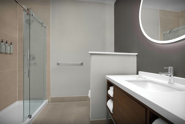 A modern bathroom with a glass shower enclosure, a white vanity with a mirror, and a towel rack.