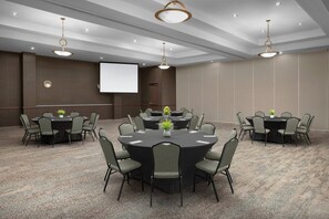 A conference room with round tables, chairs, a projector screen, and ceiling lights. - Courtyard by Marriott San Antonio SeaWorld - Westover Hills (San Antonio)