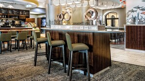 A modern bar area with a central island, bar stools, and a menu board. - Courtyard by Marriott San Antonio SeaWorld - Westover Hills (San Antonio)