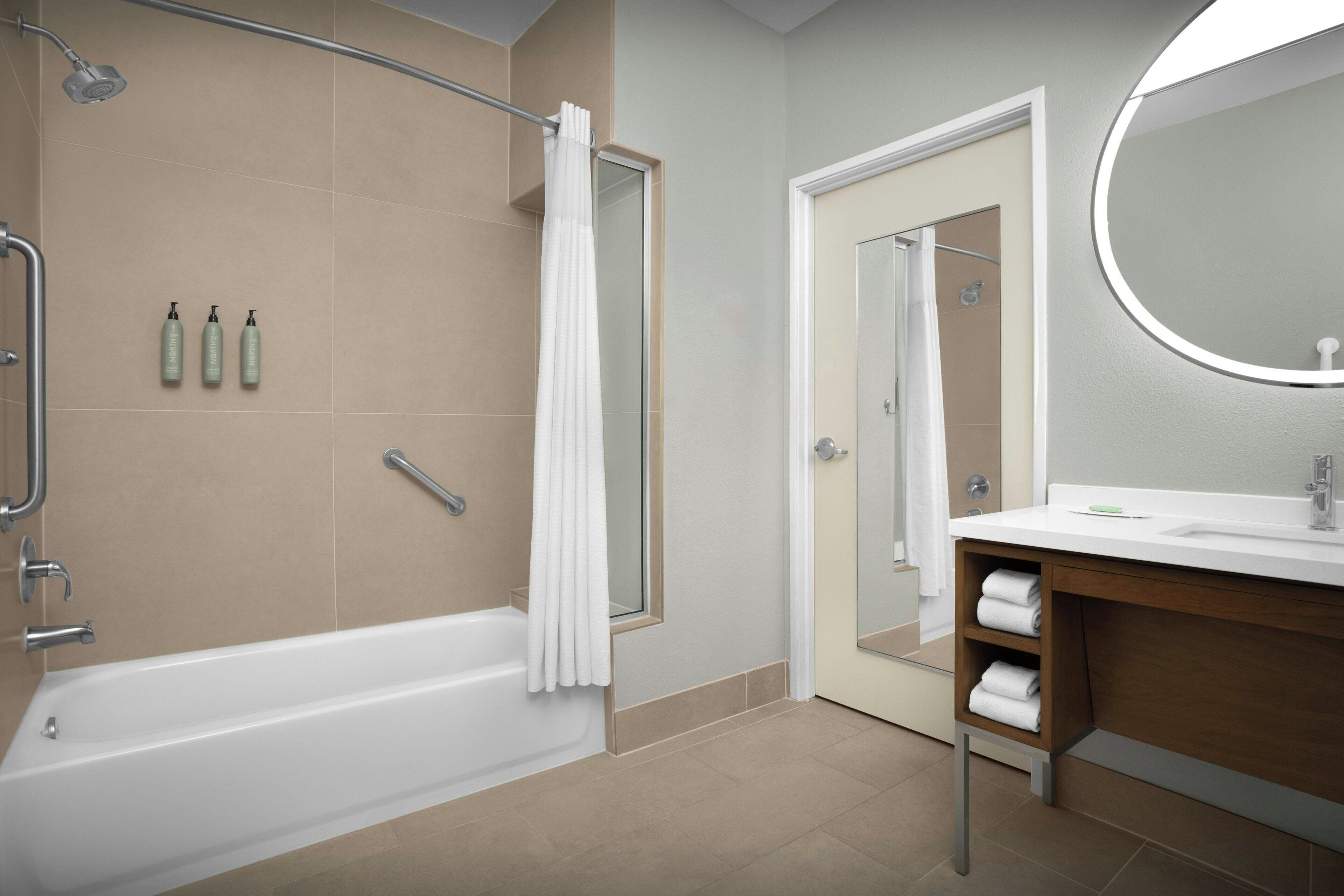 A modern bathroom with a bathtub, shower, and vanity.