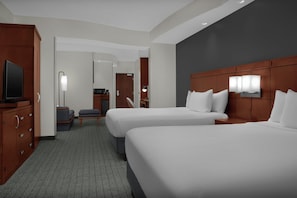 Habitación de hotel con dos camas, un televisor, un escritorio y una silla.
