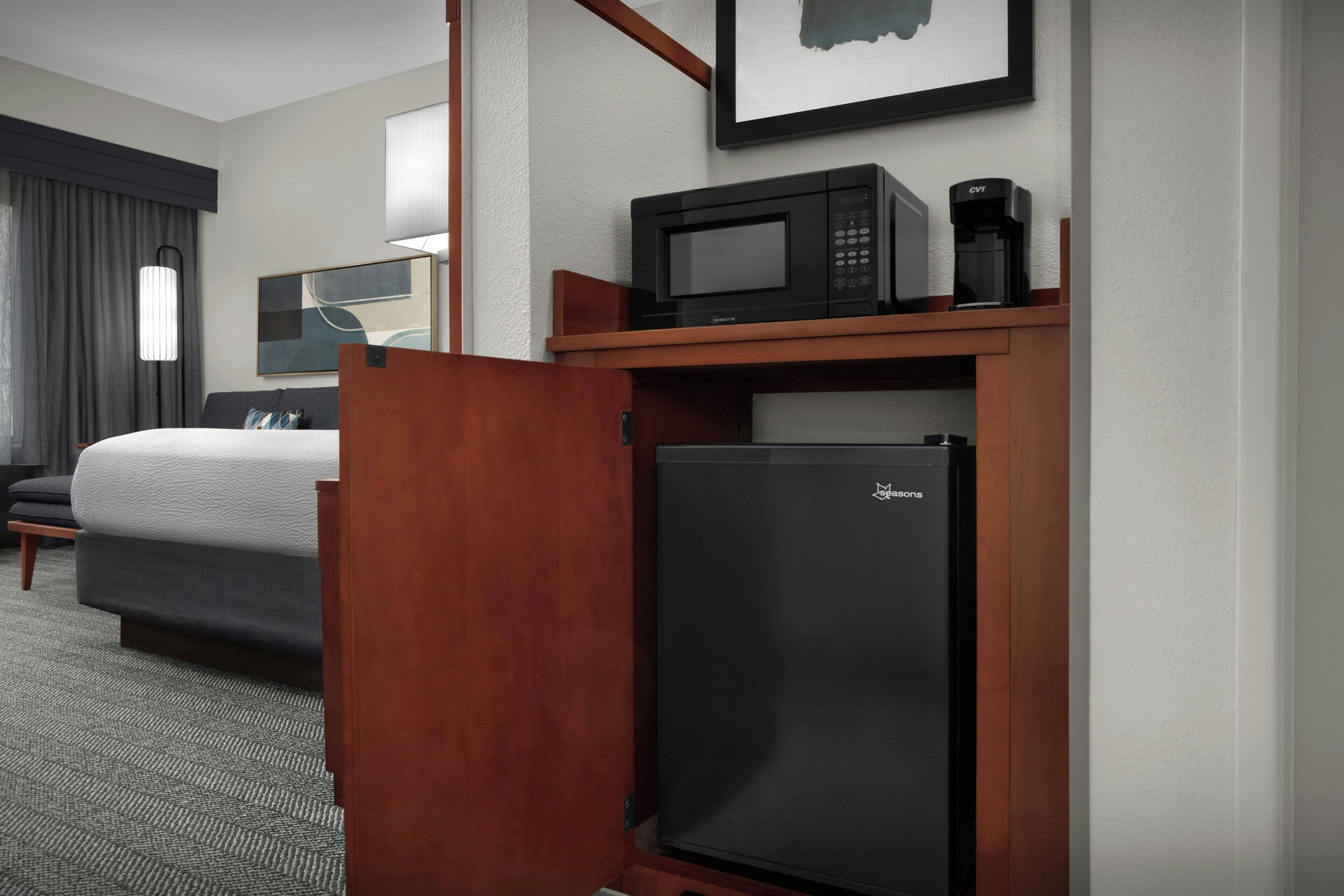 A hotel room with a bed, a minibar, a refrigerator, and a television.