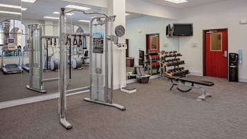 A gym with cardio machines, weight benches, and dumbbells.