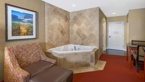 Ein Badezimmer mit einer großen Badewanne, einem gerahmten Bild an der Wand und einem roten Teppich.
