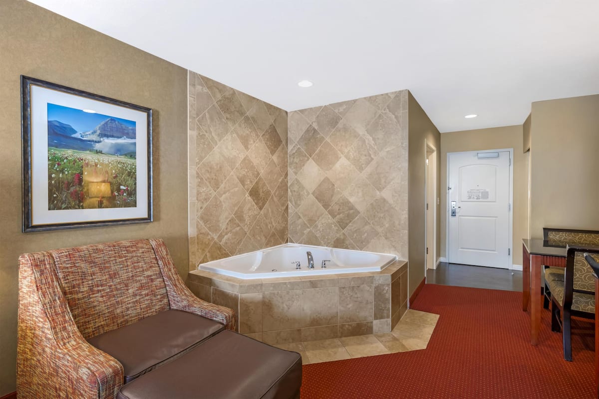 A bathroom with a large bathtub, a framed picture on the wall, and a red carpet.