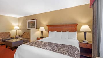 A hotel room with a large bed, two bedside tables with lamps, a sofa, and a small table.
