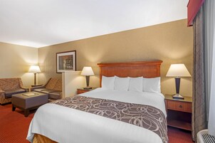Una habitación de hotel con una cama grande, dos mesitas de noche con lámparas, un sofá y una pequeña mesa.