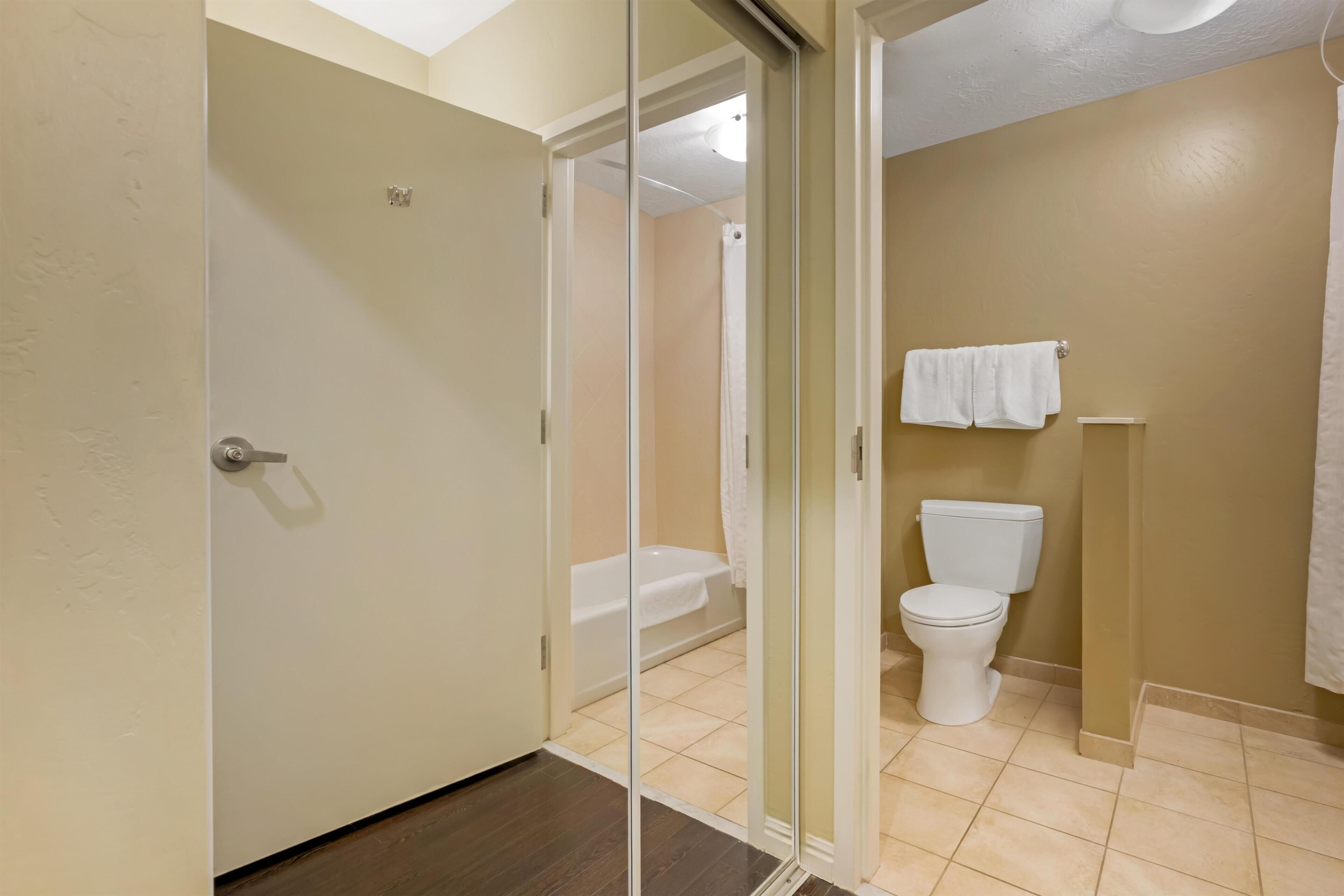 Un baño con inodoro, bañera y cabina de ducha de vidrio.