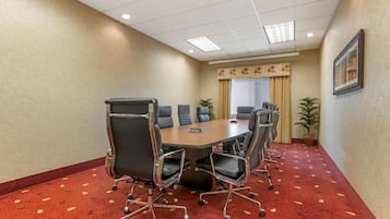 A conference room with a large table, six chairs, and a potted plant.