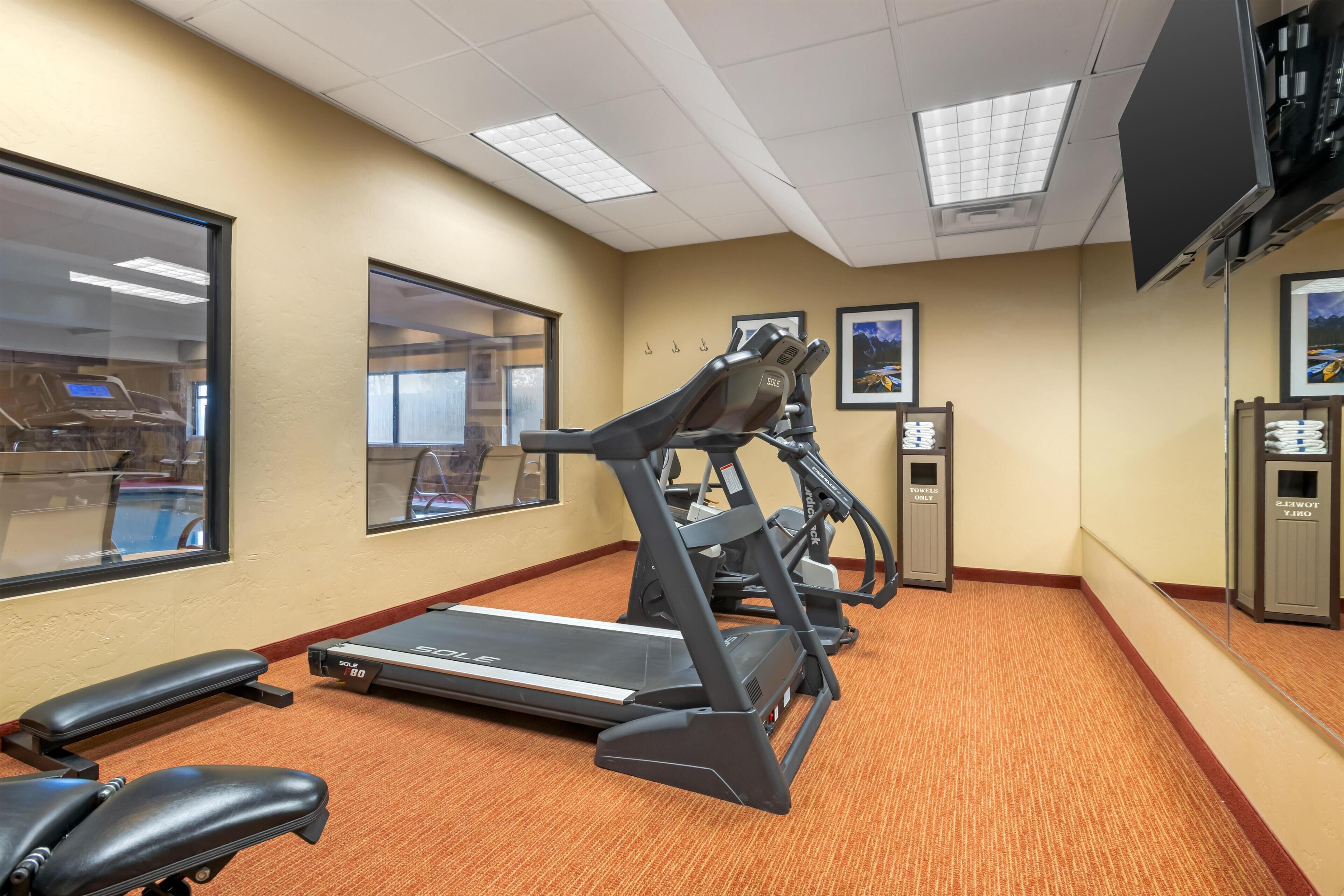 A gym with treadmills, a stationary bike, and a bench.