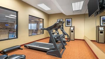 A gym with treadmills, a stationary bike, and a bench.